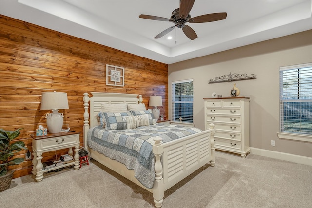 bedroom featuring multiple windows, light colored carpet, ceiling fan, and wood walls