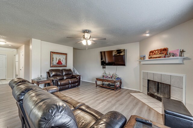 living room featuring a textured ceiling, light hardwood / wood-style flooring, and a tiled fireplace