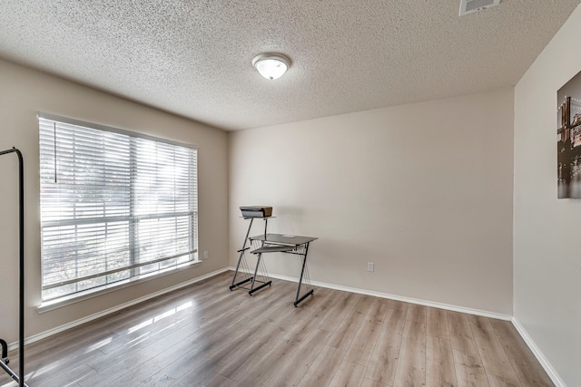 interior space with a textured ceiling and light hardwood / wood-style flooring