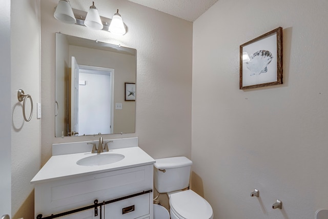 bathroom featuring vanity, toilet, and a textured ceiling