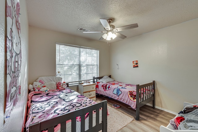 bedroom with a textured ceiling, light hardwood / wood-style flooring, and ceiling fan