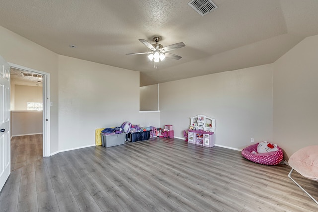 playroom with ceiling fan, light wood-type flooring, and a textured ceiling