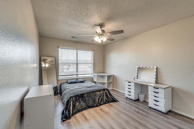 bedroom with ceiling fan, light hardwood / wood-style floors, and a textured ceiling