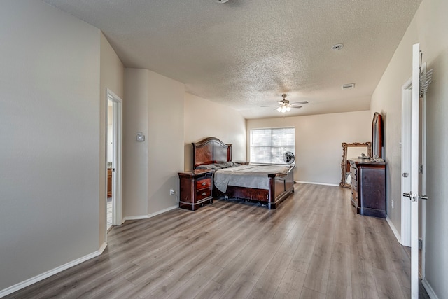 bedroom featuring ceiling fan, light hardwood / wood-style floors, and a textured ceiling