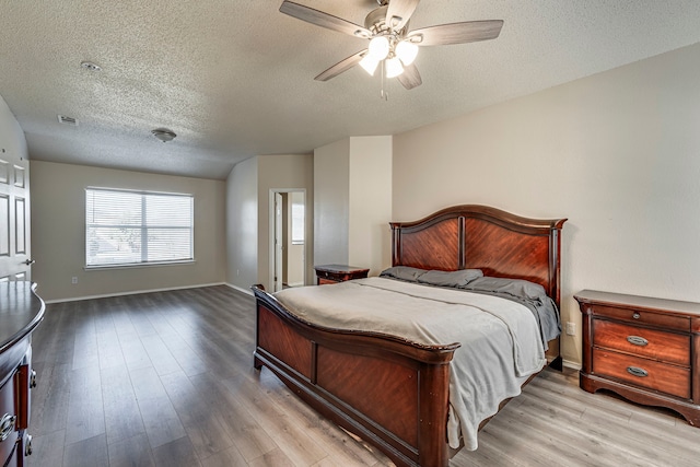 bedroom featuring ceiling fan, a textured ceiling, and light wood-type flooring