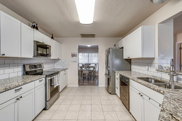 kitchen with light stone countertops, white cabinetry, sink, and black appliances