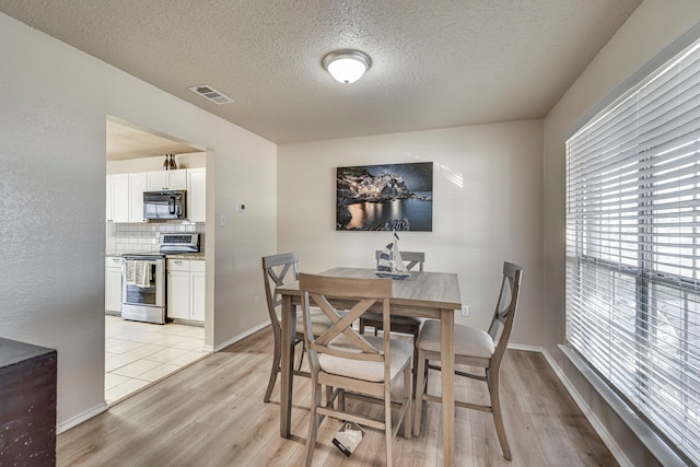 dining space with light hardwood / wood-style flooring and a textured ceiling