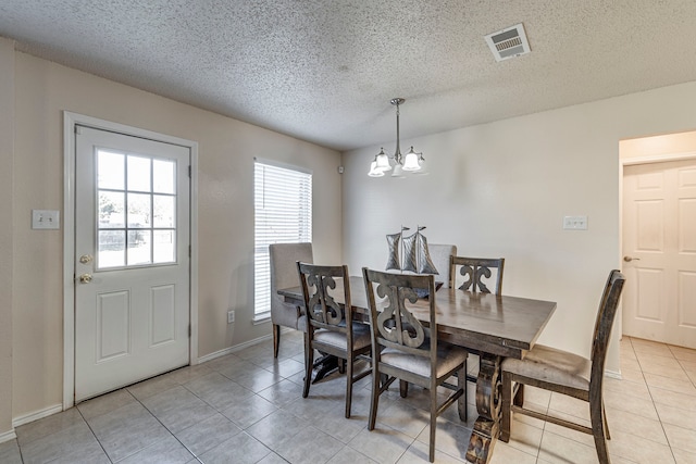 tiled dining area featuring a textured ceiling and a notable chandelier