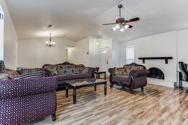 living room with a fireplace, ceiling fan with notable chandelier, light hardwood / wood-style flooring, and lofted ceiling