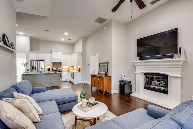 living room featuring ceiling fan, dark hardwood / wood-style flooring, sink, and a high ceiling