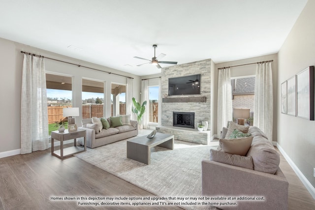 living room featuring hardwood / wood-style floors, a stone fireplace, and ceiling fan