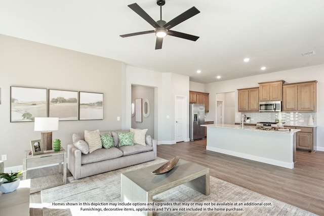 living room featuring ceiling fan, light hardwood / wood-style flooring, and sink