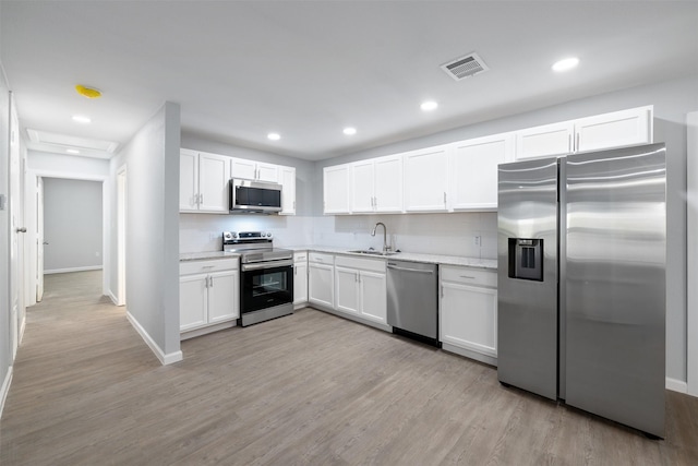 kitchen featuring sink, white cabinets, stainless steel appliances, and light hardwood / wood-style floors