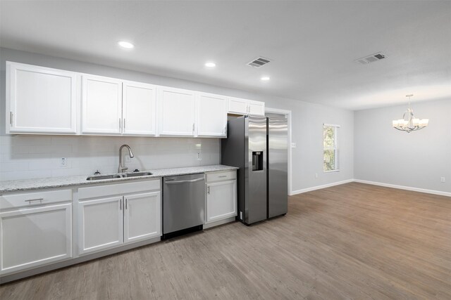 kitchen with light wood-type flooring, tasteful backsplash, stainless steel appliances, sink, and white cabinetry