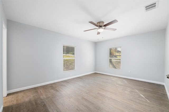 spare room with ceiling fan, wood-type flooring, and a wealth of natural light