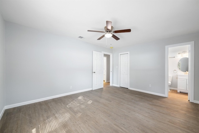 unfurnished bedroom featuring ceiling fan, wood-type flooring, connected bathroom, and a closet