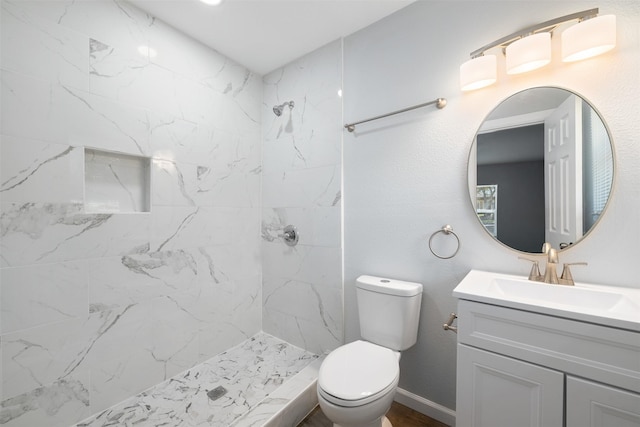 bathroom featuring vanity, toilet, and tiled shower