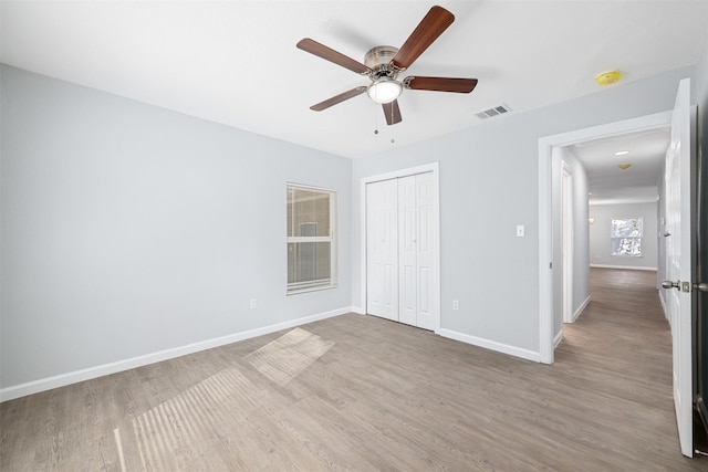 unfurnished bedroom featuring a closet, hardwood / wood-style flooring, and ceiling fan