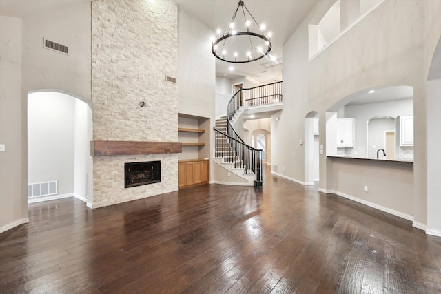 unfurnished living room featuring wood-type flooring, a fireplace, visible vents, and baseboards