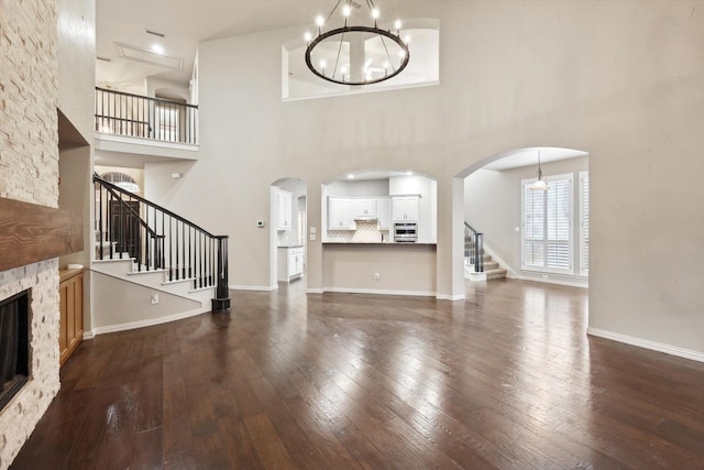 2543 Sir Tristram Ln, Lewisville, TX 75056 - unfurnished living room featuring stairs, dark wood finished floors, a high ceiling, a stone fireplace, and a chandelier