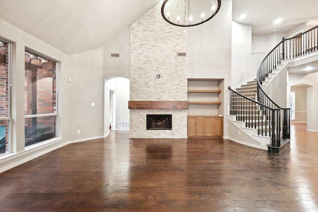 2543 Sir Tristram Ln, Lewisville, TX 75056 - unfurnished living room featuring arched walkways, high vaulted ceiling, hardwood / wood-style floors, a fireplace, and stairs