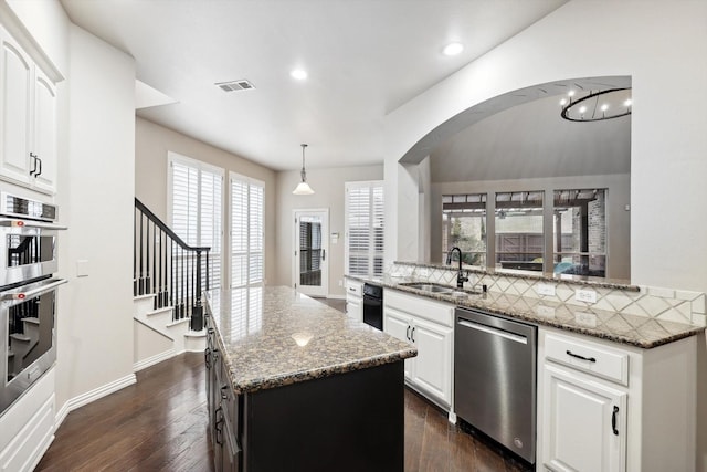 2543 Sir Tristram Ln, Lewisville, TX 75056 - kitchen with stainless steel appliances, a sink, a center island, dark wood-style flooring, and light stone counters