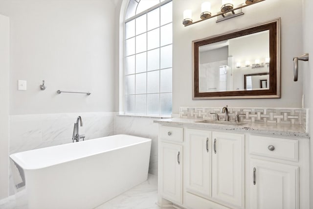 2543 Sir Tristram Ln, Lewisville, TX 75056 - full bath with a freestanding tub, vanity, marble look tile flooring, tile walls, and a wainscoted wall