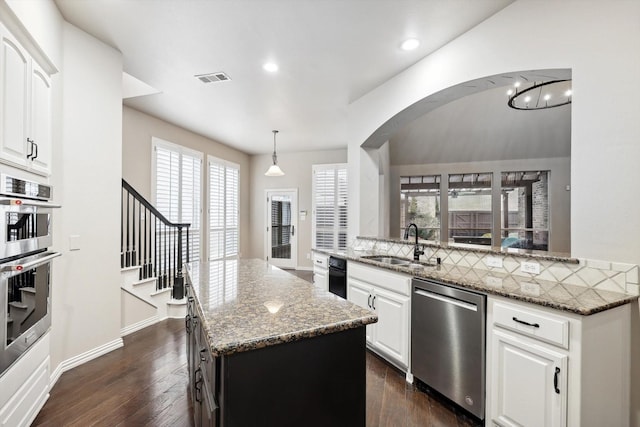 kitchen with pendant lighting, appliances with stainless steel finishes, white cabinetry, a center island, and dark stone countertops