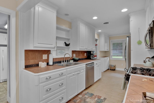 kitchen featuring sink, crown molding, tasteful backsplash, appliances with stainless steel finishes, and white cabinets