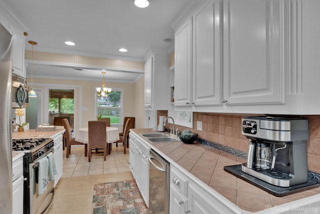 kitchen with sink, white cabinetry, hanging light fixtures, stainless steel appliances, and tile counters