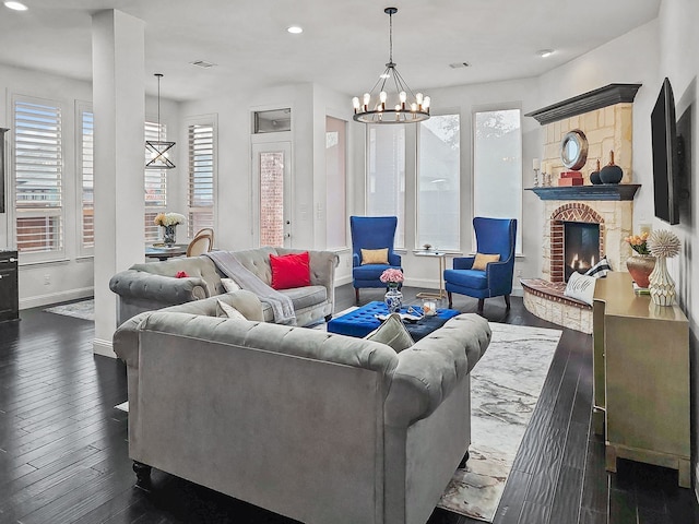 living room featuring a stone fireplace, a chandelier, and dark wood-type flooring