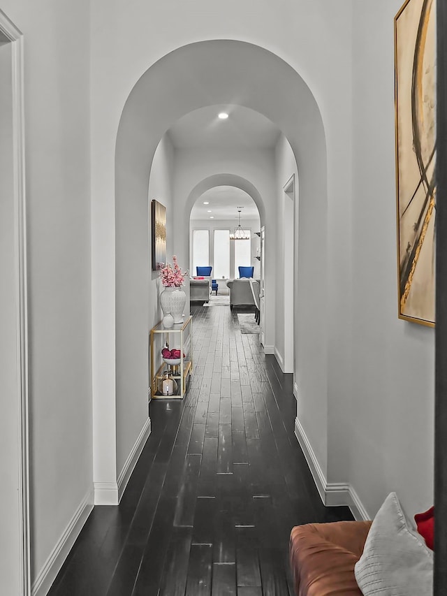 hall featuring dark hardwood / wood-style floors and a chandelier