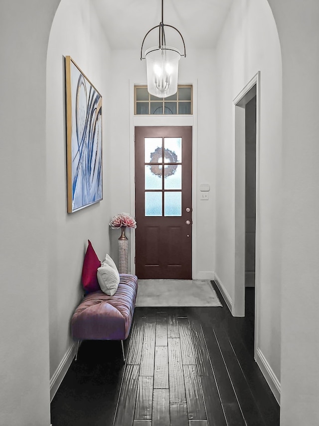 foyer entrance with a chandelier and dark wood-type flooring