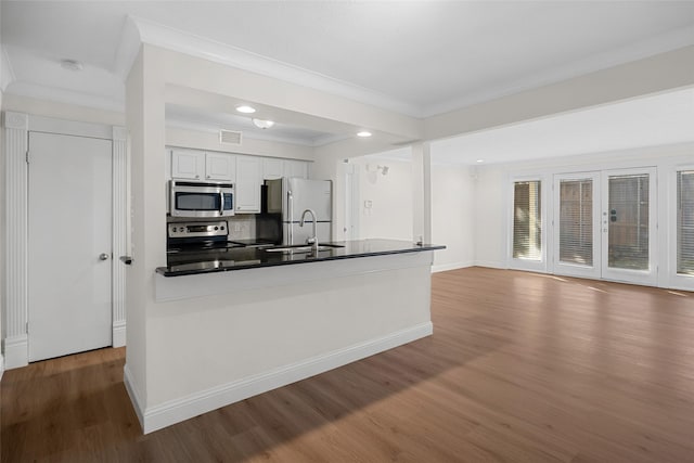 kitchen with a sink, dark countertops, stainless steel appliances, a peninsula, and crown molding