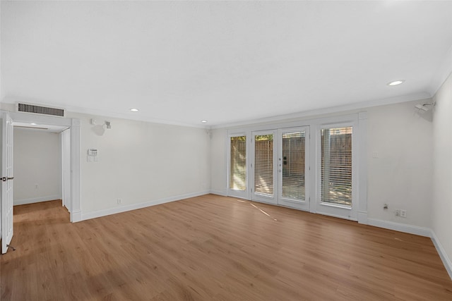 spare room featuring french doors, crown molding, and light hardwood / wood-style flooring