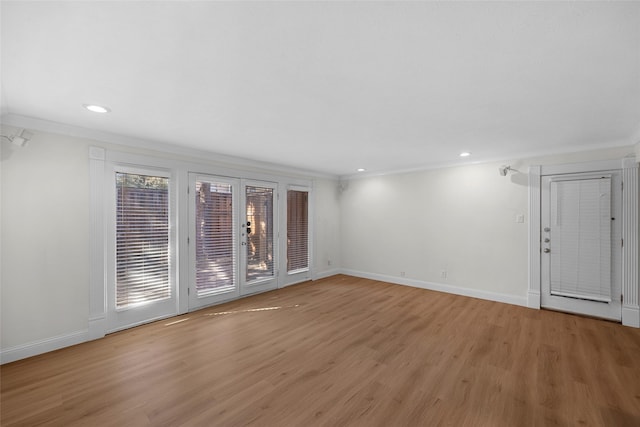 spare room with baseboards, crown molding, and light wood-style floors