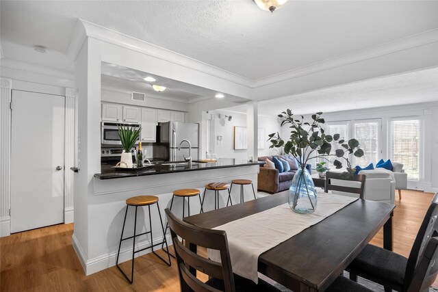 kitchen with light hardwood / wood-style flooring, backsplash, crown molding, white cabinets, and appliances with stainless steel finishes