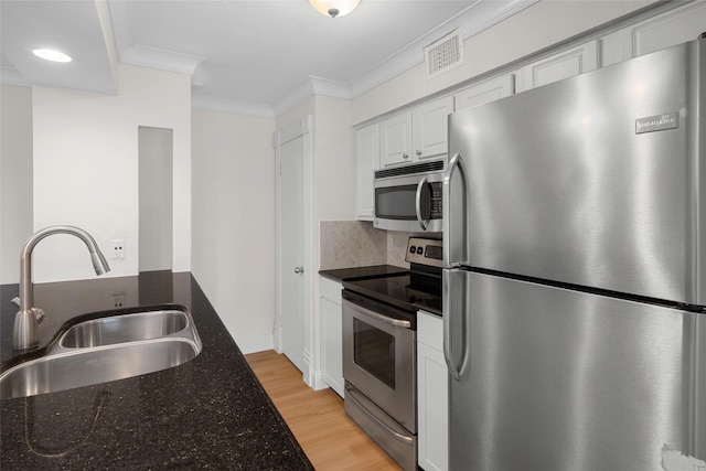 kitchen featuring white cabinetry, sink, dark stone countertops, crown molding, and appliances with stainless steel finishes