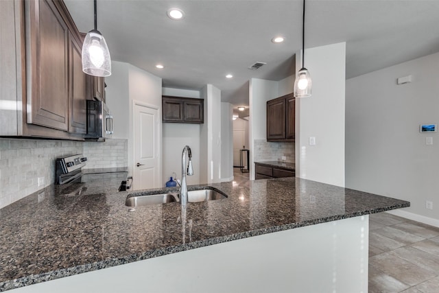 kitchen featuring pendant lighting, sink, dark stone countertops, appliances with stainless steel finishes, and kitchen peninsula