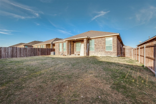 rear view of house with central AC and a lawn