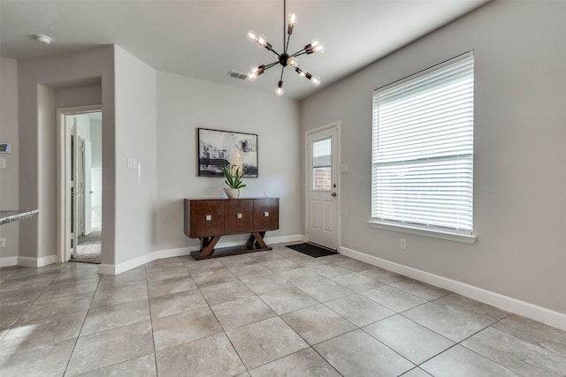 tiled foyer entrance featuring an inviting chandelier