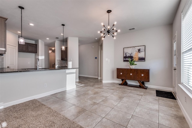 kitchen with sink, backsplash, a chandelier, decorative light fixtures, and dark brown cabinets