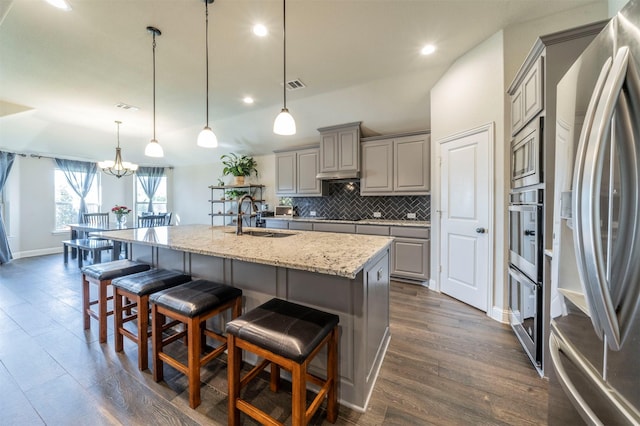 kitchen featuring sink, hanging light fixtures, a kitchen breakfast bar, stainless steel appliances, and a kitchen island with sink