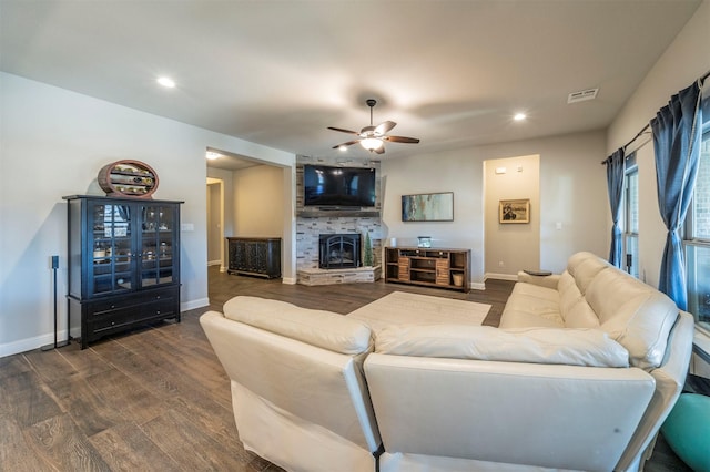 living room featuring dark wood-type flooring, ceiling fan, and a fireplace