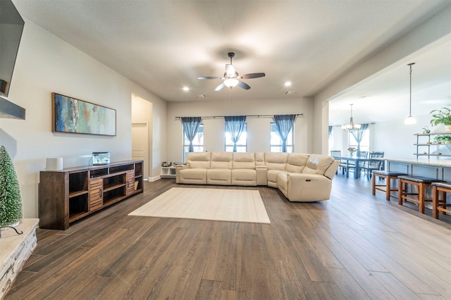 living room with dark wood-type flooring, plenty of natural light, and ceiling fan with notable chandelier