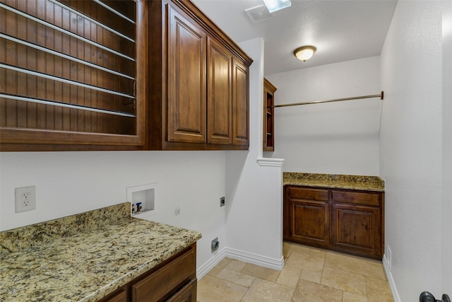 clothes washing area with hookup for a washing machine, baseboards, cabinet space, electric dryer hookup, and stone tile flooring