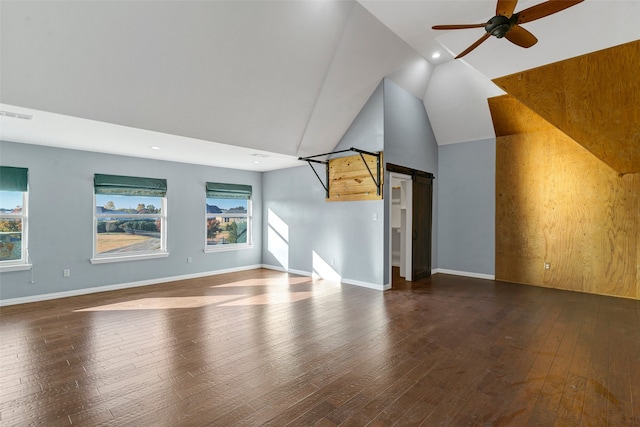 additional living space featuring a wealth of natural light, wood-type flooring, visible vents, a barn door, and ceiling fan