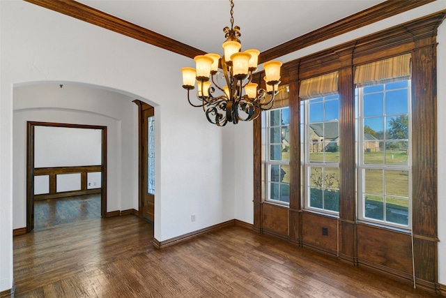 unfurnished dining area with arched walkways, dark wood-style flooring, crown molding, and baseboards