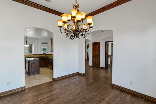 unfurnished dining area with arched walkways, baseboards, wood finished floors, and crown molding