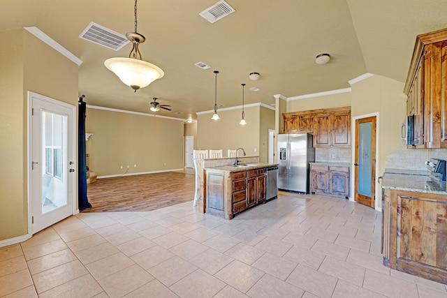 kitchen with ceiling fan, tasteful backsplash, decorative light fixtures, a kitchen island with sink, and appliances with stainless steel finishes